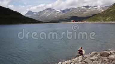 年轻的女旅行者坐在岩石上欣赏<strong>山湖美景</strong>